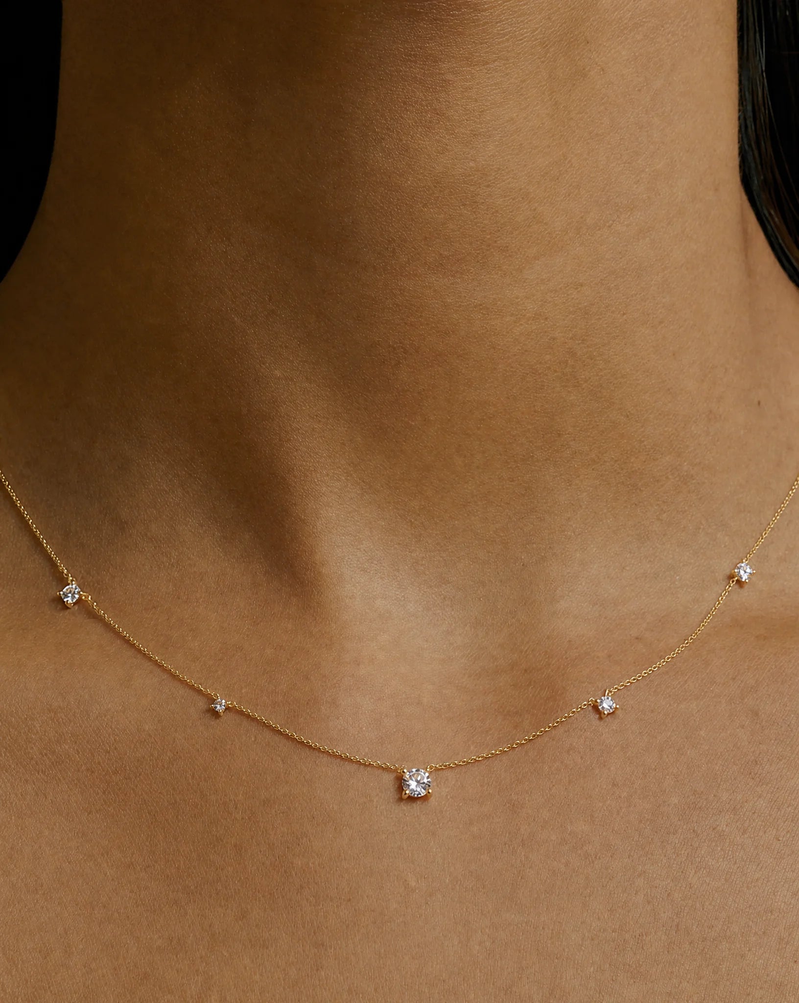 Celeste Satellite Necklace in yellow gold featuring a central round stone and four satellite-set stones on a delicate fine chain, worn on a model.