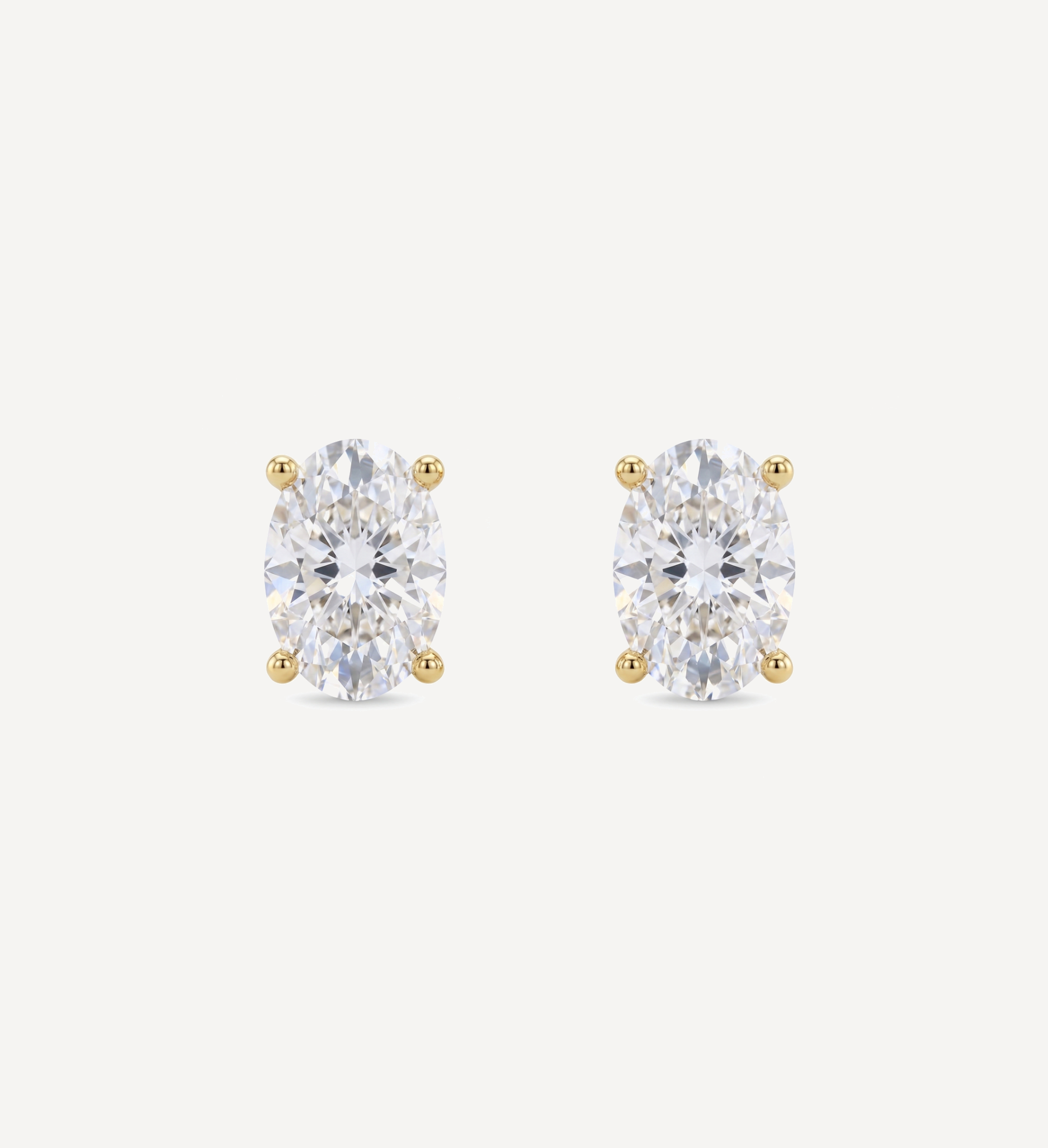 Large Oval Grace diamond stud earrings in yellow gold featuring oval brilliant-cut diamonds, shown in front and side profile with a four-prong setting and butterfly back